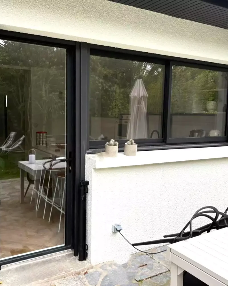 Porte-fenêtre coulissante aluminium noire installée à Pacé par Artimob Menuiserie, expert en menuiserie sur mesure.